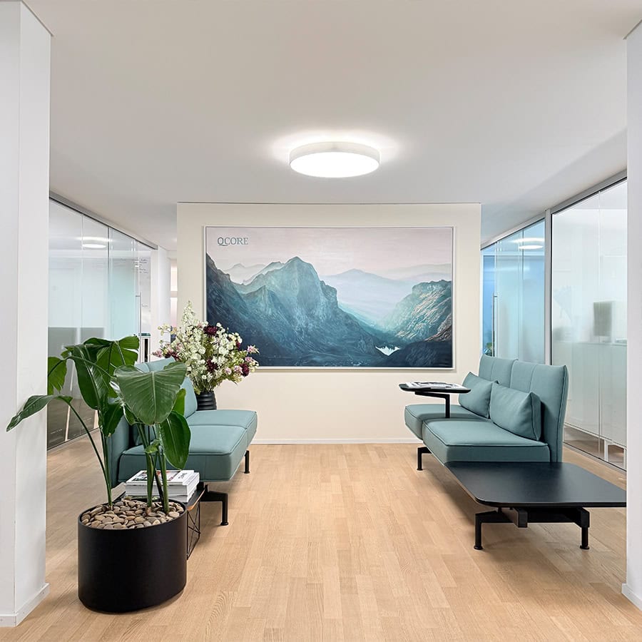 Serene modern office lounge with artwork and plants Stylish, tranquil office waiting area featuring artwork, lush plants, and comfortable seating, shipped worldwide by Nikolaus Kriese. Detailed image showing a modern, minimalistic reception area with pastel turquoise seating, potted plant, and a large mountain landscape painting by Nikolaus Kriese, available for worldwide shipping.