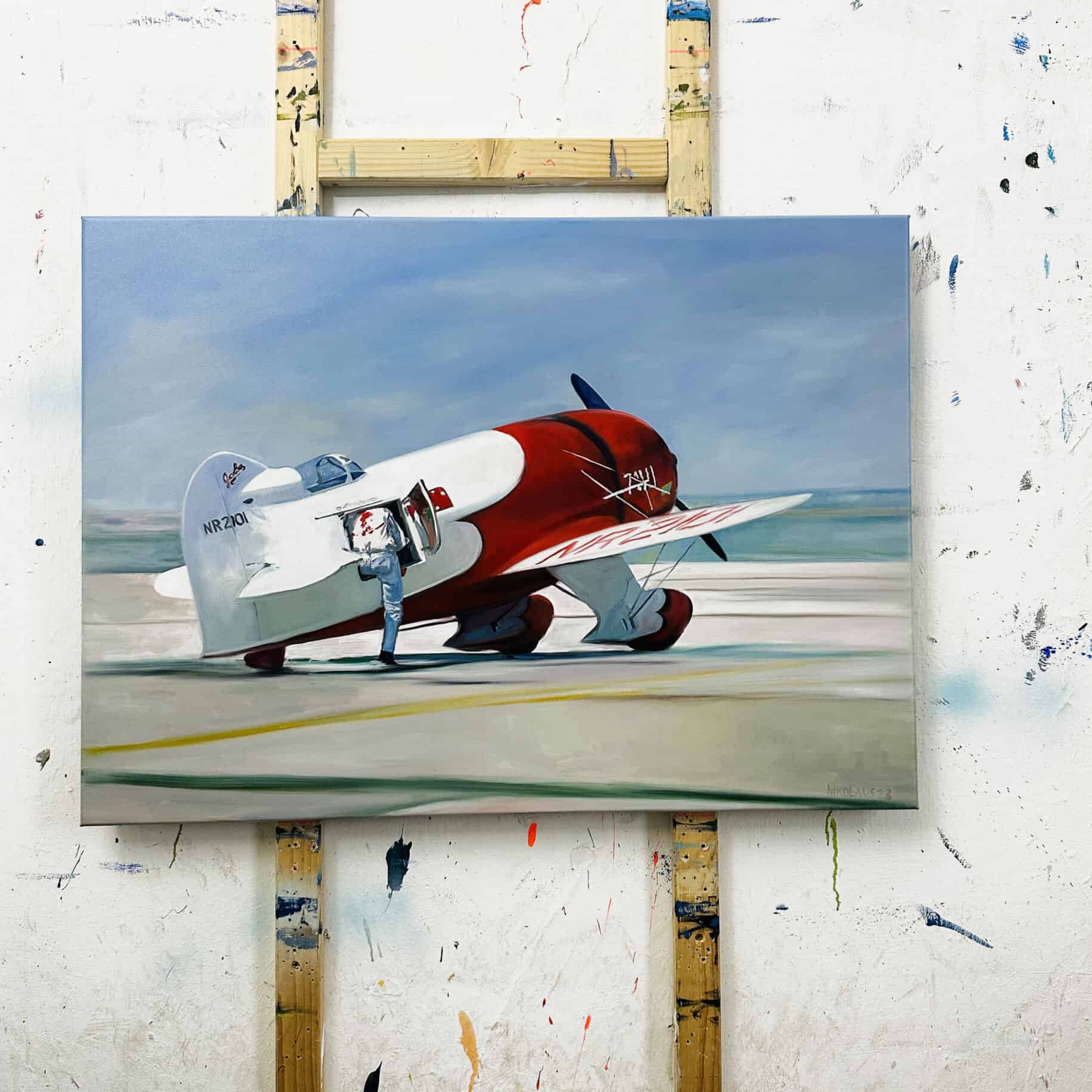 Powered aircraft on a runway, painted in red and white, with a clear sky background.