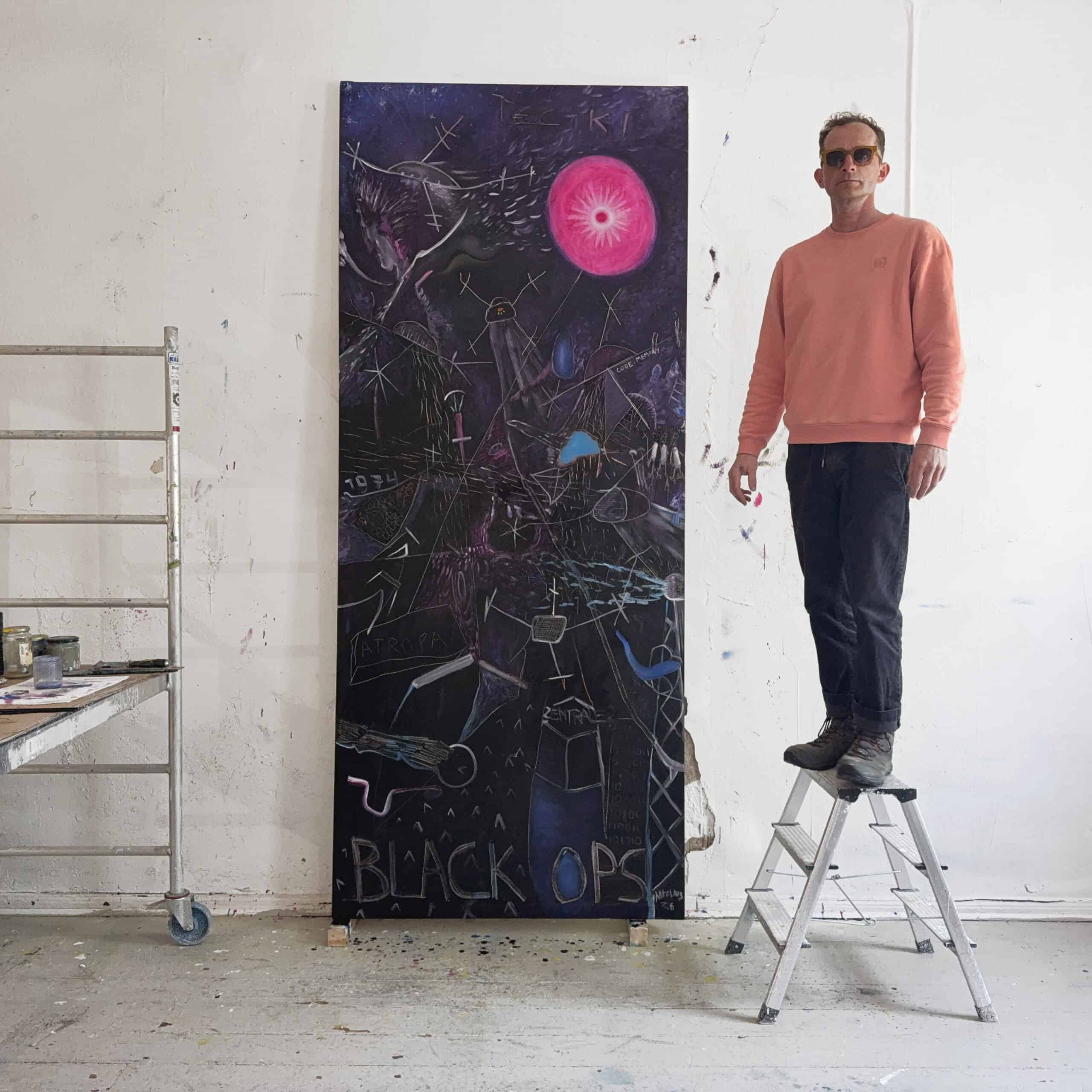 Nikolaus Kriese standing on a ladder next to his large abstract painting titled "Black Ops," showcasing vibrant colors and complex shapes, created for a contemporary art exhibition.