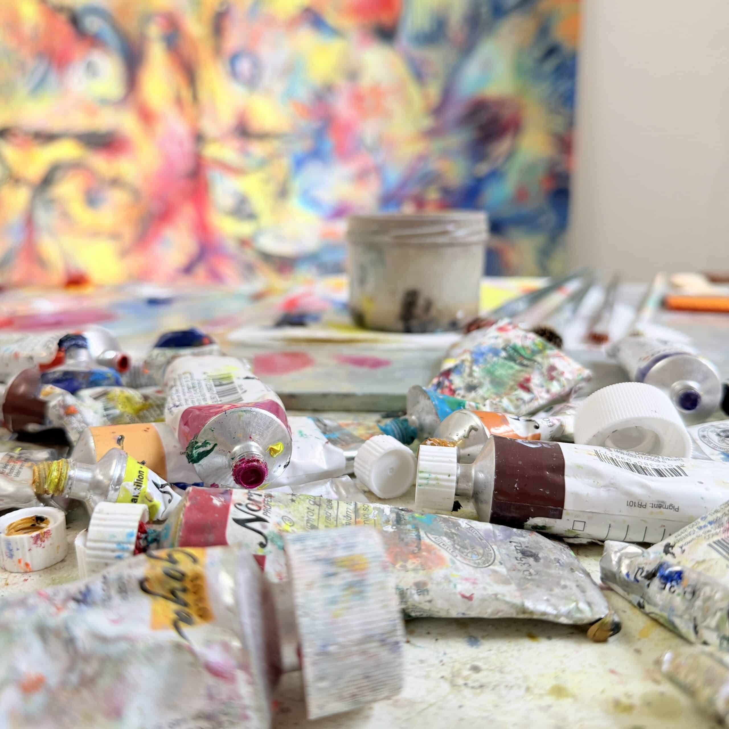 Art studio with colorful paints and supplies, showcasing the creative workspace of Nikolaus Kriese, a commissioned artist offering worldwide shipping.