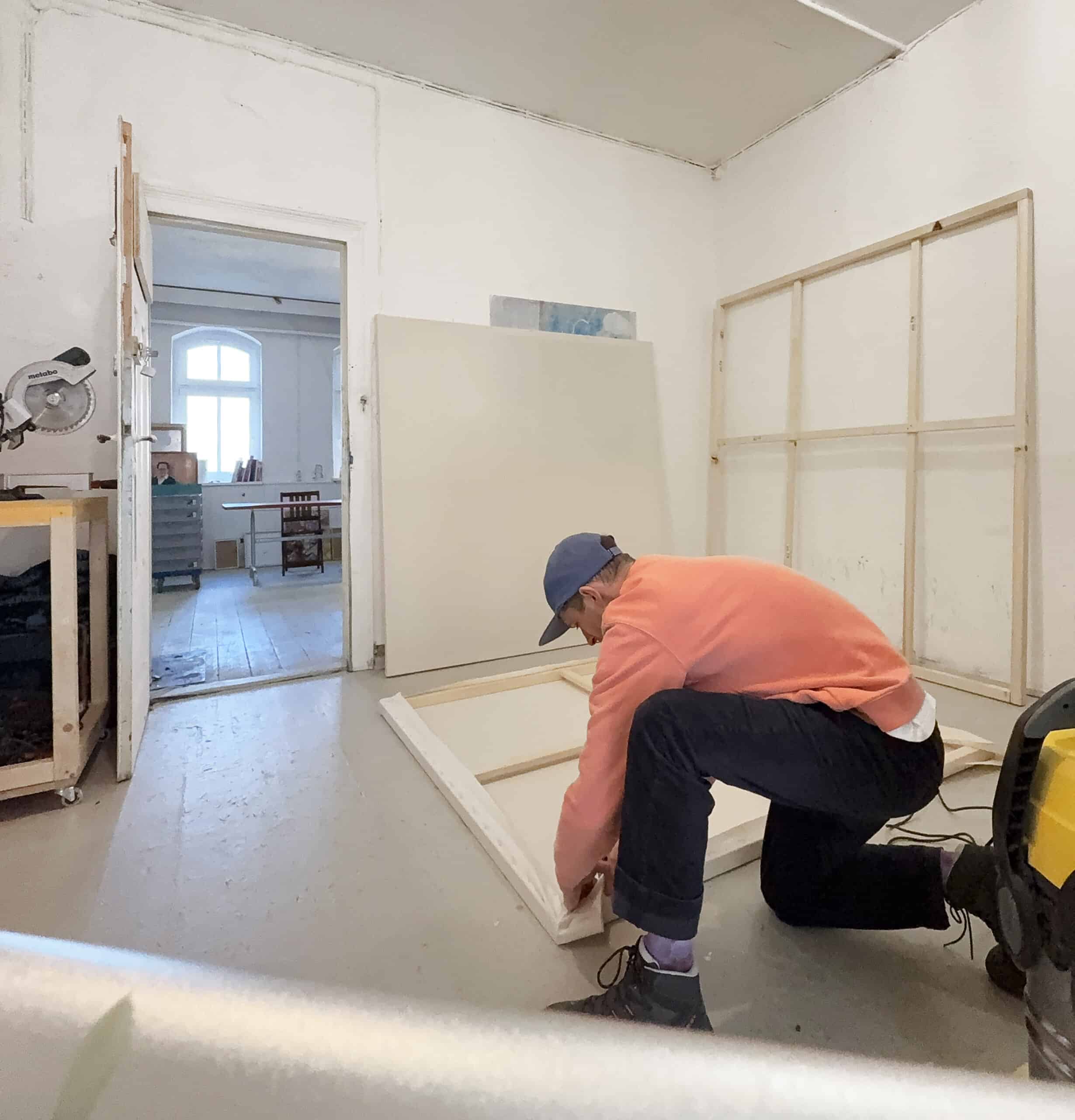 Artist working on a large canvas in his studio, preparing for a commissioned artwork.
